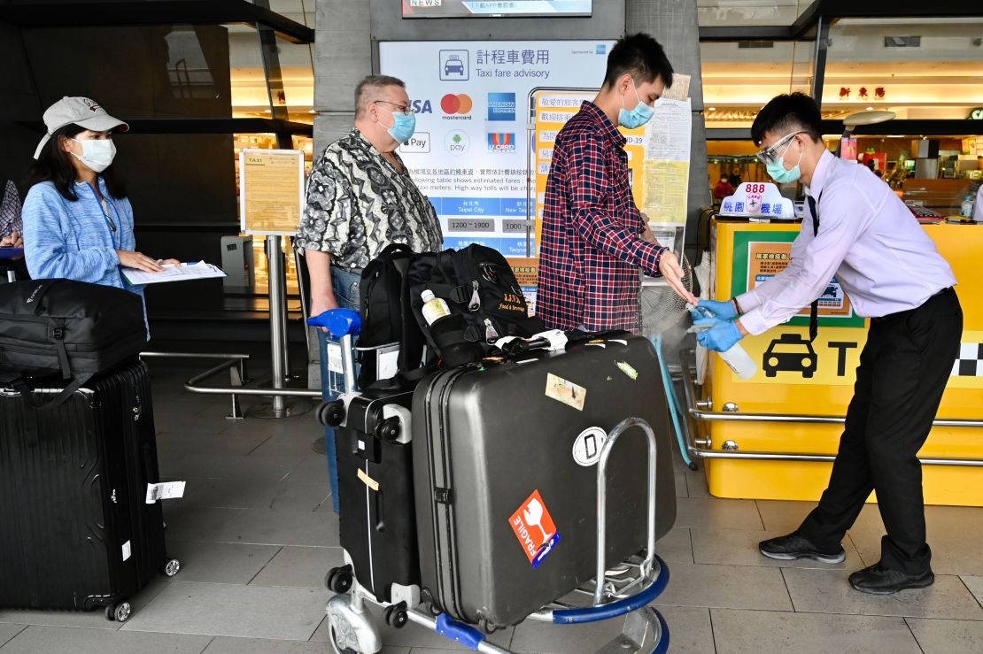 A worker sprays hand sanitiser onto passengers after they arrive at Taoyuan Airport on March 19, 2020.