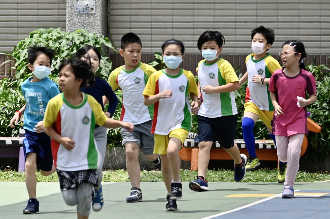Students wearing face masks run during a sports class at Dajia Elementary School in Taipei on April 29, 2020.
