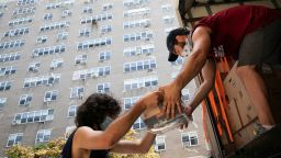 Jakob Howell, left, and Matt Brown load boxes belonging to Joyce and Anil Lilly into a moving truck, Tuesday, July 21, 2020, in The Bronx borough of New York. The Lilly's are leaving their 14th floor apartment and are moving to a town an hour's drive north, amid the coronavirus pandemic. (AP Photo/Mark Lennihan)