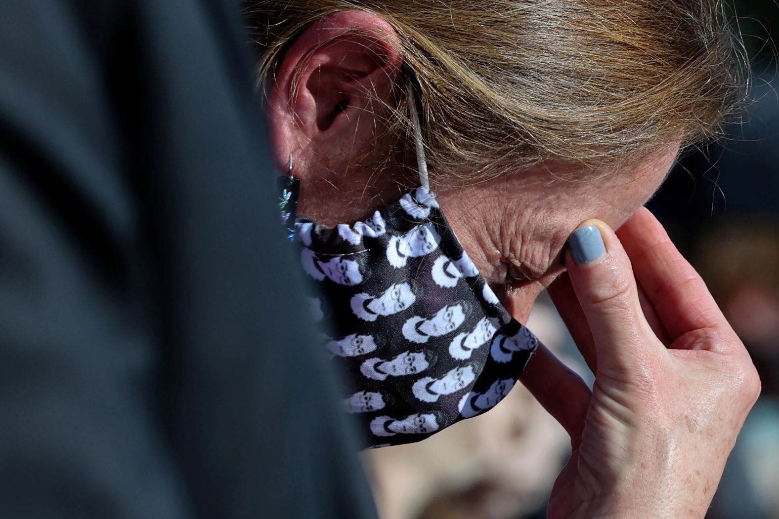 A woman mourns outside the Supreme Court while wearing a Ginsburg-themed face mask.