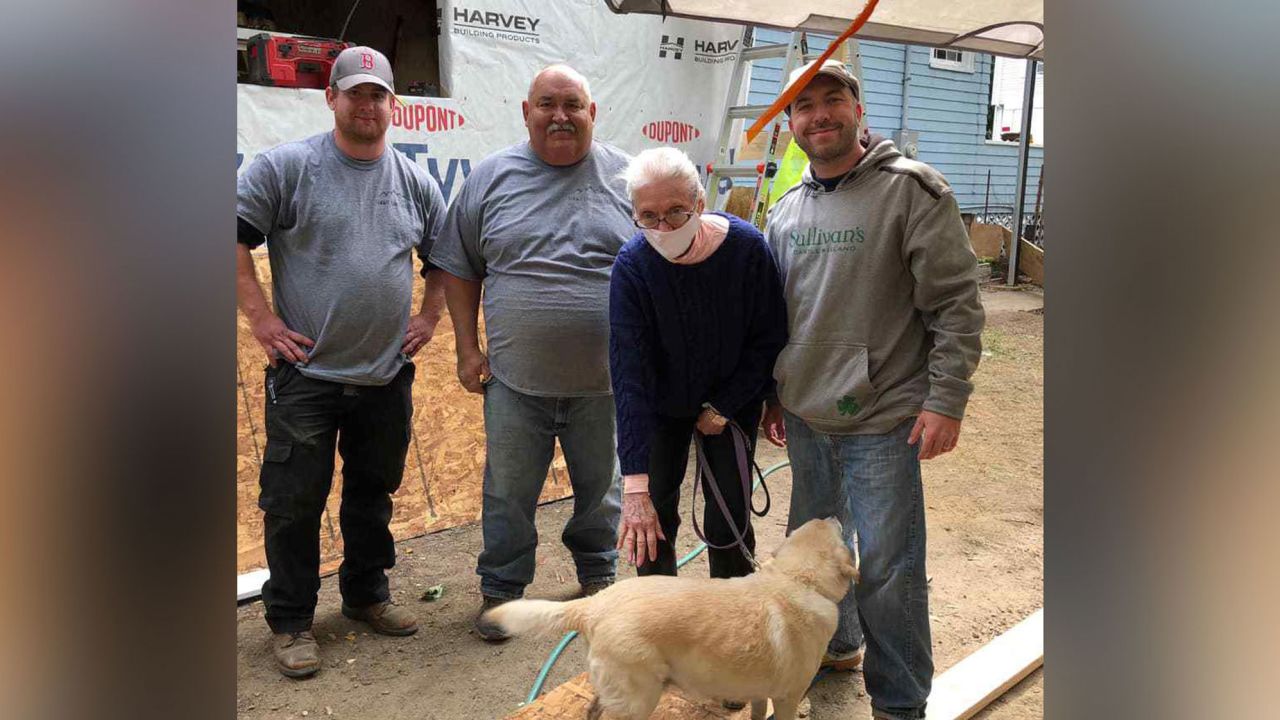 Gloria Scott is surrounded by members of the "Gloria's Gladiators" team that is rebuilding her home.