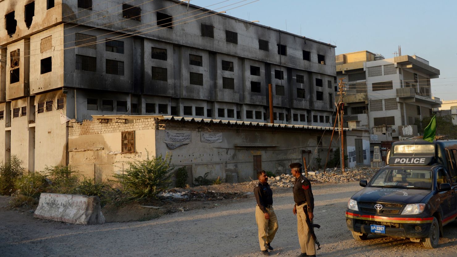 Pakistani policemen stand in front of the burnt out garment factory in Karachi. More than 260 people died in the blaze. 