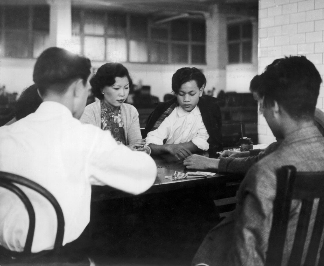 Chinese immigrants play cards while waiting in the immigration offices at Ellis Island, US, around 1940-1950.