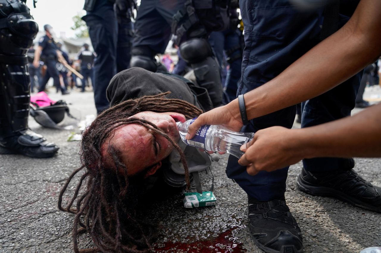 A protester in Louisville offers a detained man water.
