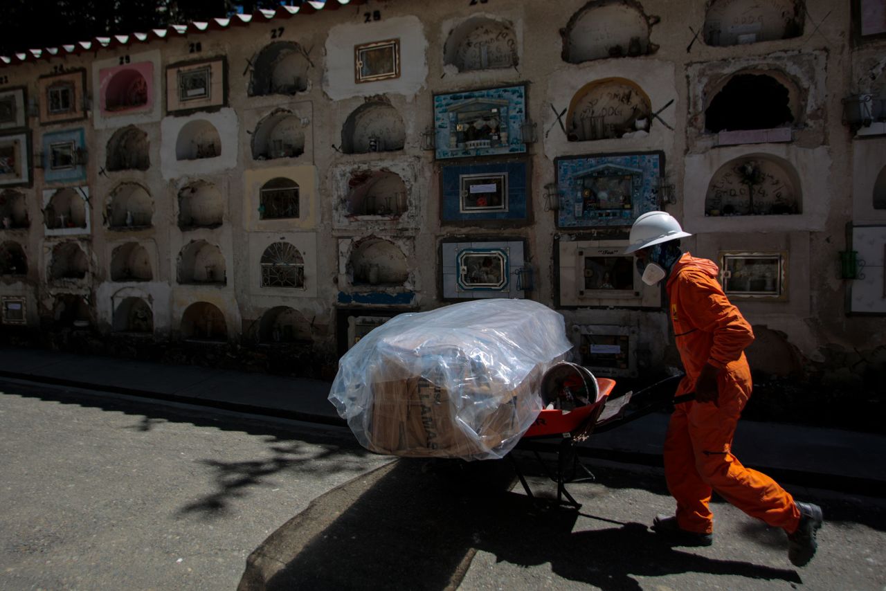 A cemetery worker in La Paz, Bolivia, pushes a cart with a plastic-wrapped coffin on September 23.