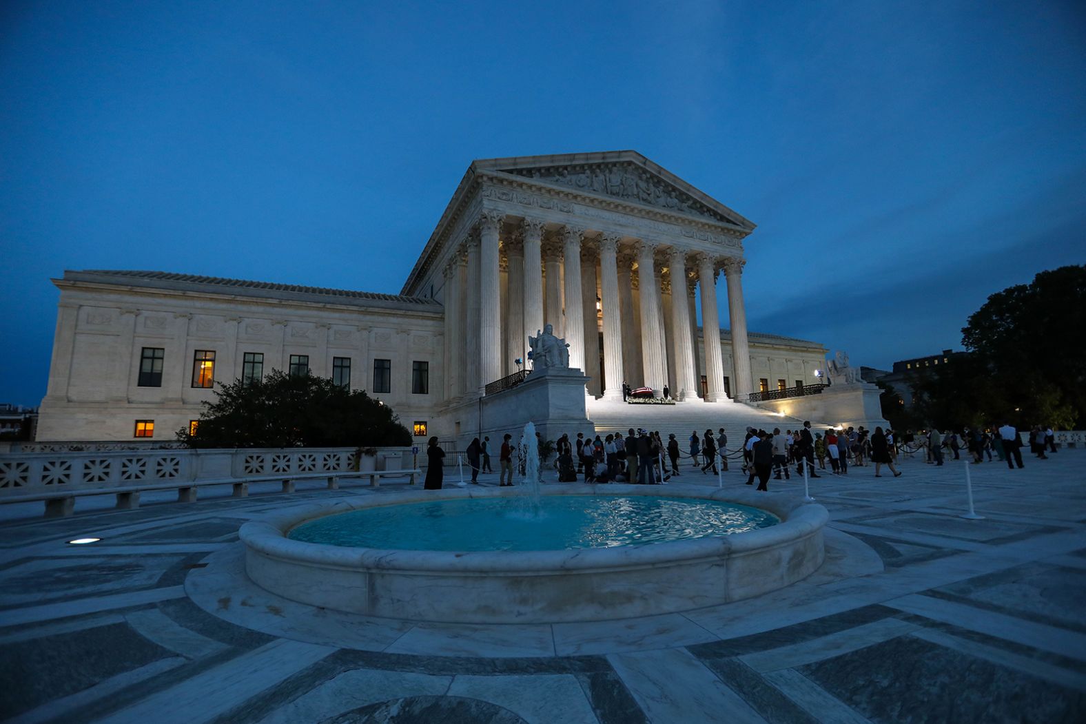 Visitors are seen on the steps of the Supreme Court building on Wednesday evening. 
