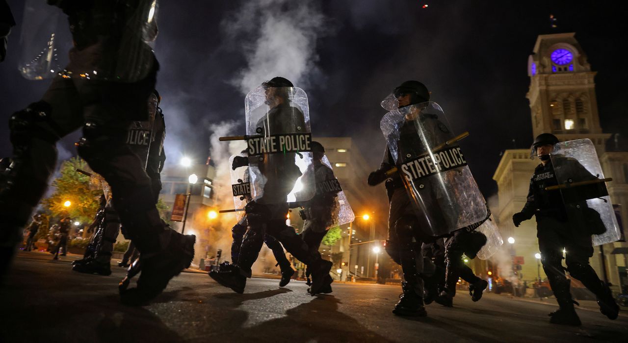 Police officers move past Louisville City Hall as a curfew is implemented at 9 p.m. to disperse protesters on September 23.
