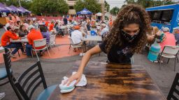 A server cleans a table in an outdoor area at a restaurant during Clemson University's first home football game in Clemson, South Carolina, U.S., on Saturday, Sept. 19, 2020. The South Carolina Department of Health and Environmental Control released the state's daily coronavirus numbers Friday showing another milestone surpassed during the outbreak: More than 3,000 deaths. Photographer: Micah Green/Bloomberg via Getty Images