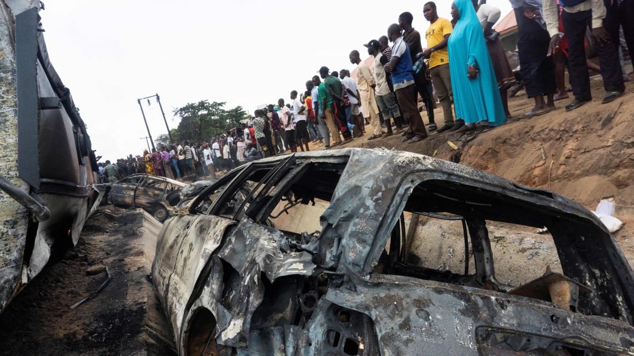 Bystanders look on at the wreckage of a truck that caught fire in Lokoja, Nigeria, on September 23, 2020. 