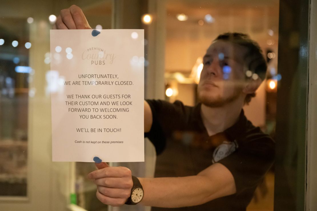 A man puts a sign in the window of the Corner House pub in Cardiff, Wales in March.