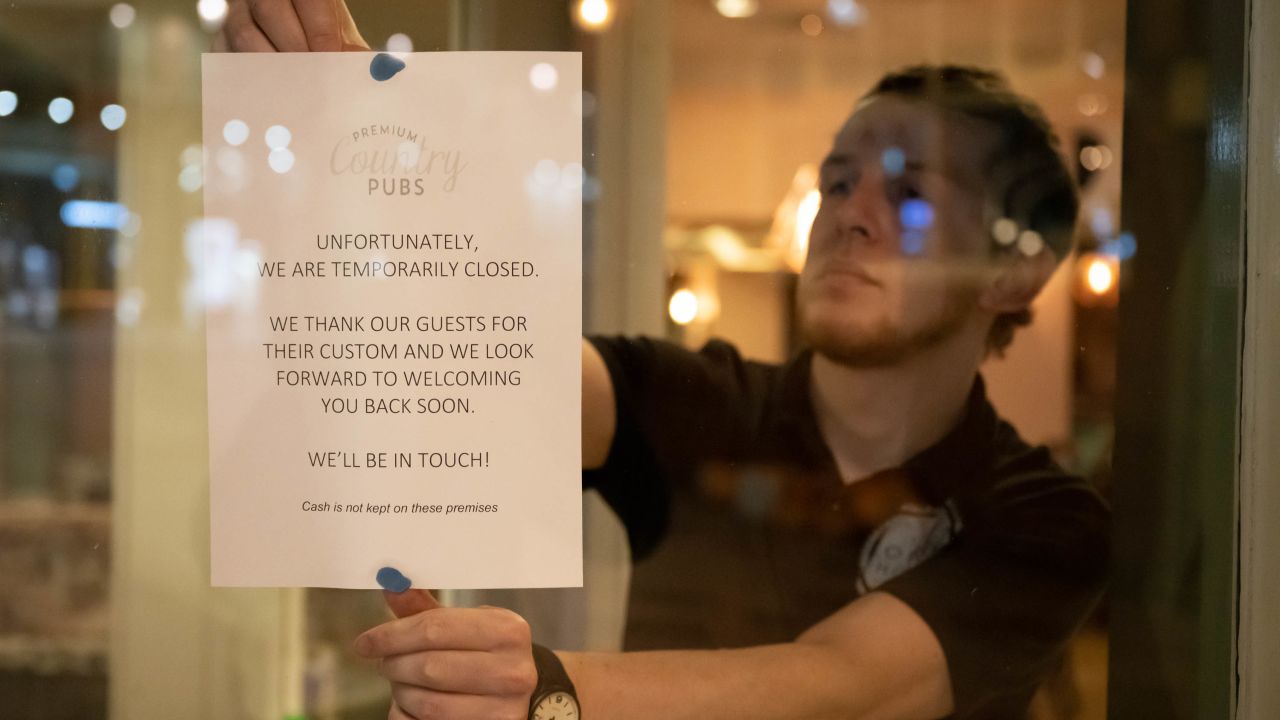 A man puts a sign in the window of the Corner House pub in Cardiff, Wales in March.