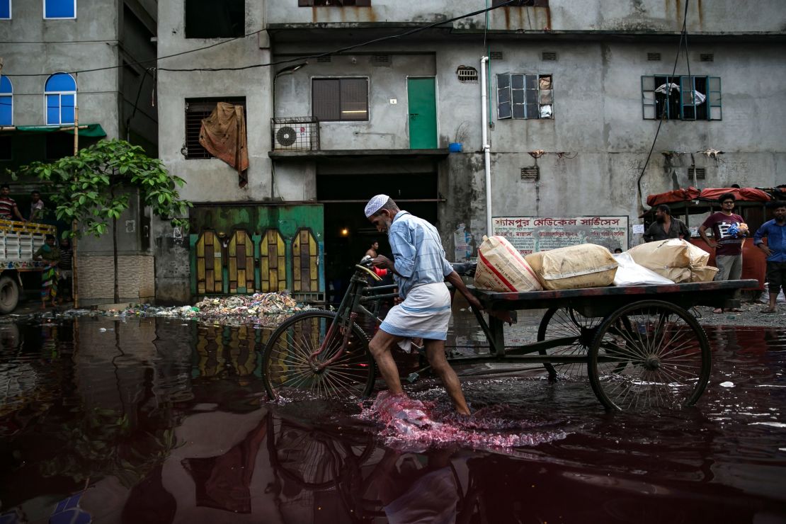 A man walks through colored rainwater past a dyeing factory in Shyampur in June 2018. Its waste is dumped into the Buriganga river in Dhaka, Bangladesh.