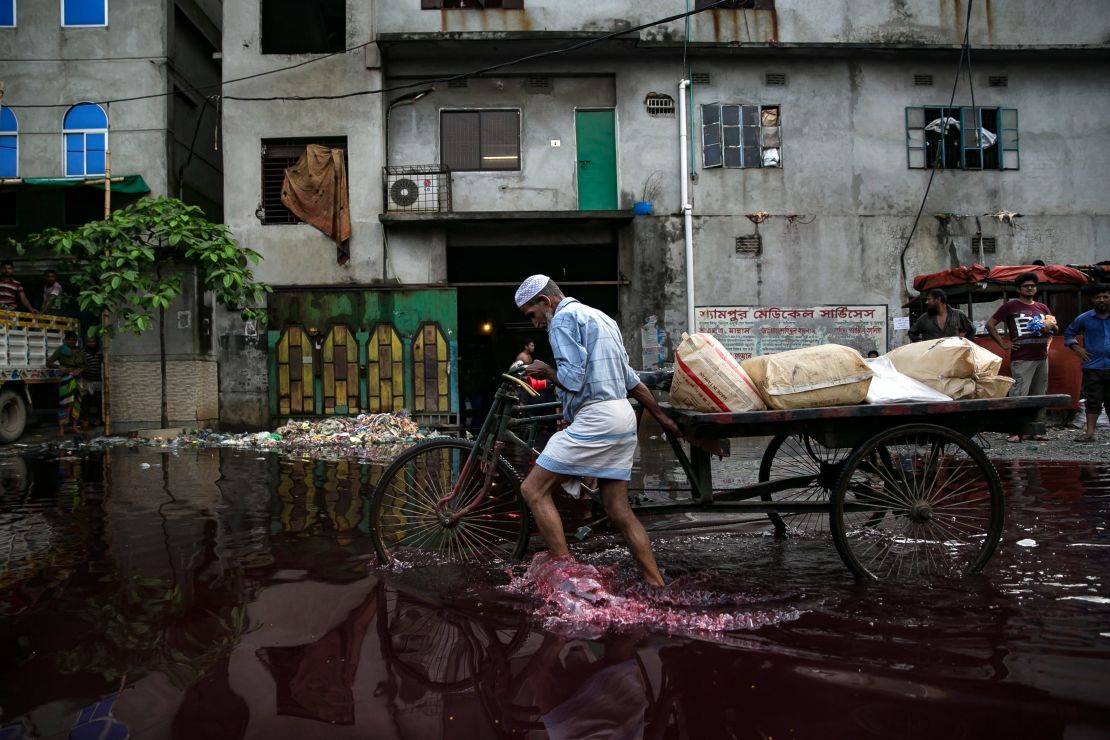 A man walks through colored rainwater past a dyeing factory in Shyampur in June 2018. Its waste is dumped into the Buriganga river in Dhaka, Bangladesh. 