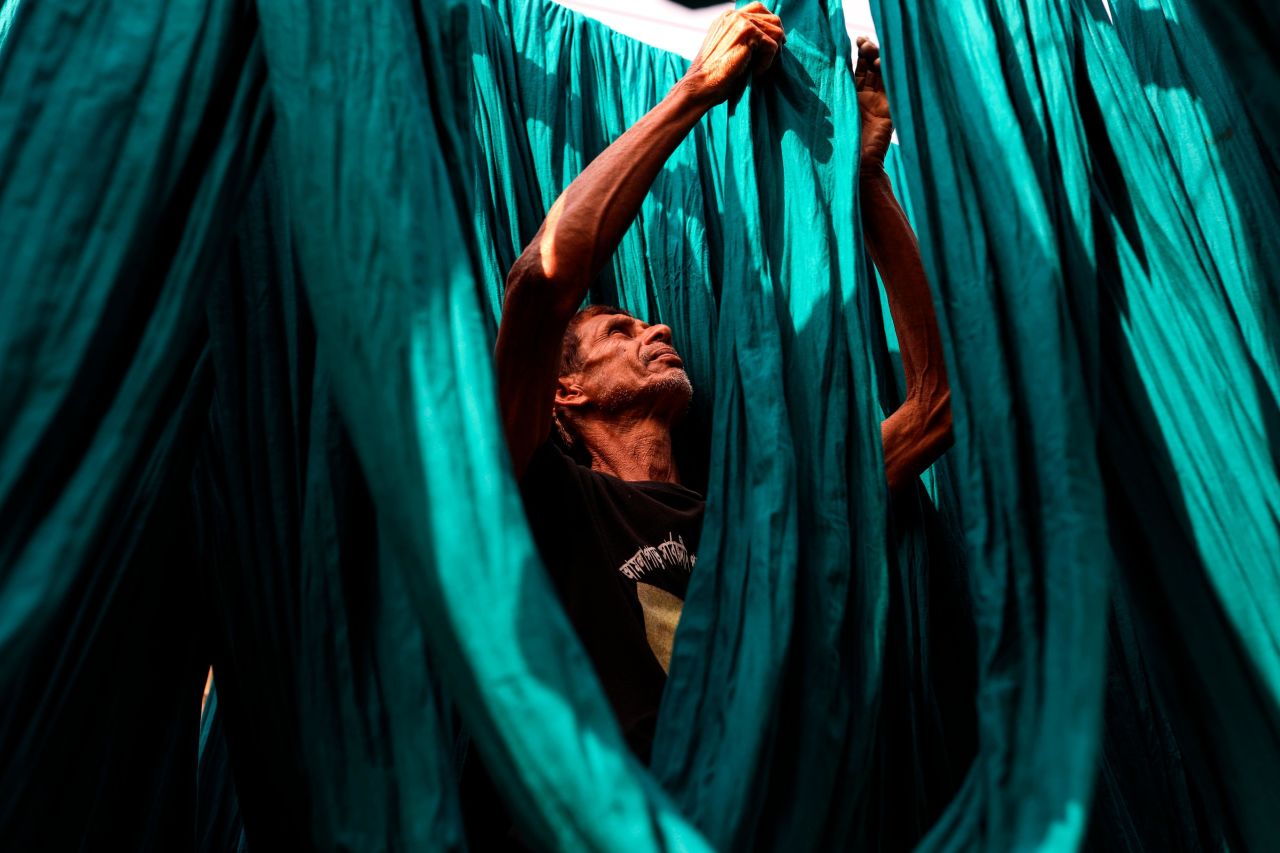A dye factory worker suns lengths of fabric after washing them in Narayanganj, near Dhaka in March 2019.