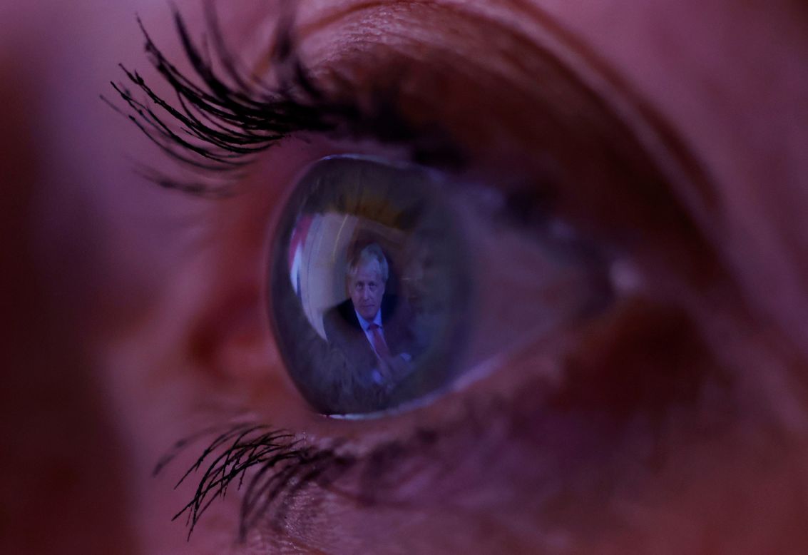 A woman watches Britain's Prime Minister Boris Johnson's address to the nation on Tuesday, September 22, in Manchester, England. Faced with a surge in coronavirus cases, Johnson announced new measures to combat the virus in England, including restrictions -- enforceable by the police -- on how people can socialize.