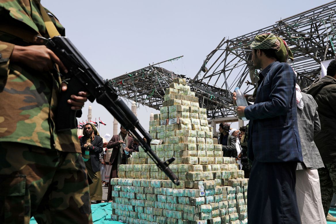 Houthis stand near Yemeni currency in Sanaa, Yemen, during a ceremony to collect supplies for their fighters battling government forces on Thursday, September 24.