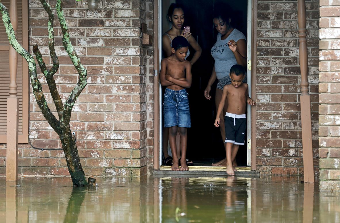 Adrian Murray, 4, dips his toes into his flooded front lawn following Tropical Storm Beta in Houston while Cam'ron Maltie, 8, and family watch on Tuesday, September 22. 