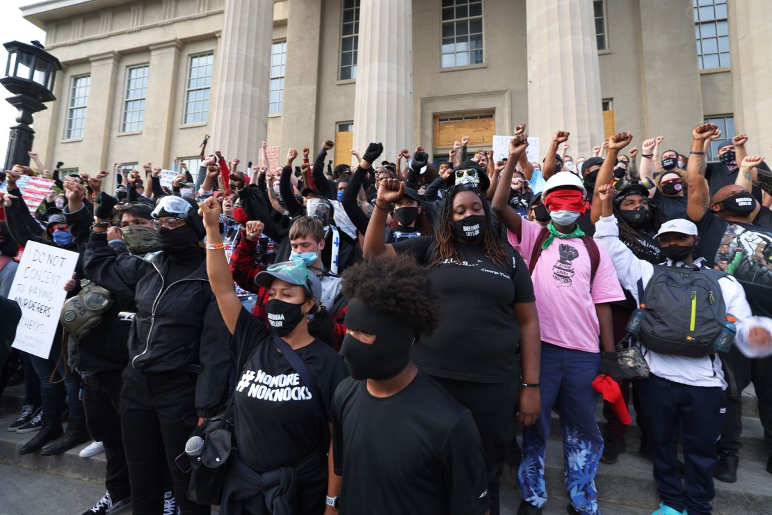 Demonstrators raise their fists as they gather on the steps of the Louisville Metro Hall on September 24, 2020.