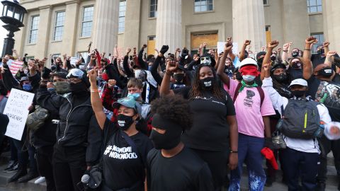 Demonstrators raise their fists as they gather on the steps of the Louisville Metro Hall on September 24, 2020.
