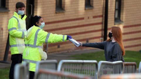Staff from the UK's National Health Service (NHS) hand out test kits to Glasgow University students as they arrive at a pop up test center at the Murano Street Student Village residence.