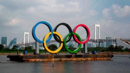 A large size Olympic rings symbol (W32.6m x H15.3m) is seen in front of Rainbow Bridge at Tokyo Waterfront in the waters of Odaiba Marine Park on August 6, 2020 while being transferred back to the factory where it was manufactured for a safety inspection and to receive maintenance. (Photo by Behrouz MEHRI / AFP) (Photo by BEHROUZ MEHRI/AFP via Getty Images)