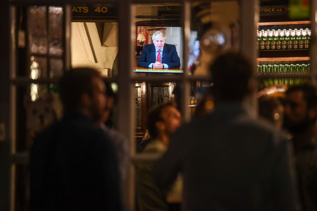 Drinkers at the Westminster Arms pub in London watch as British PM Boris Johnson makes a televised address to the nation on Tuesday.