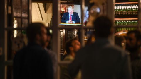 Drinkers at the Westminster Arms pub in London watch as British PM Boris Johnson makes a televised address to the nation on Tuesday.