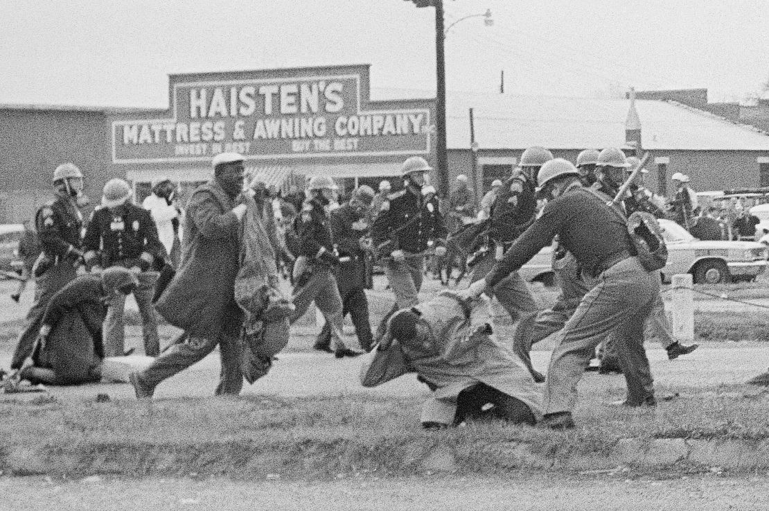 In this March 1965 photo, a state trooper swings a billy club at John Lewis, right foreground, chairman of the Student Nonviolent Coordinating Committee, to break up a civil rights voting march in Selma, Alabama. Lewis sustained a fractured skull. 