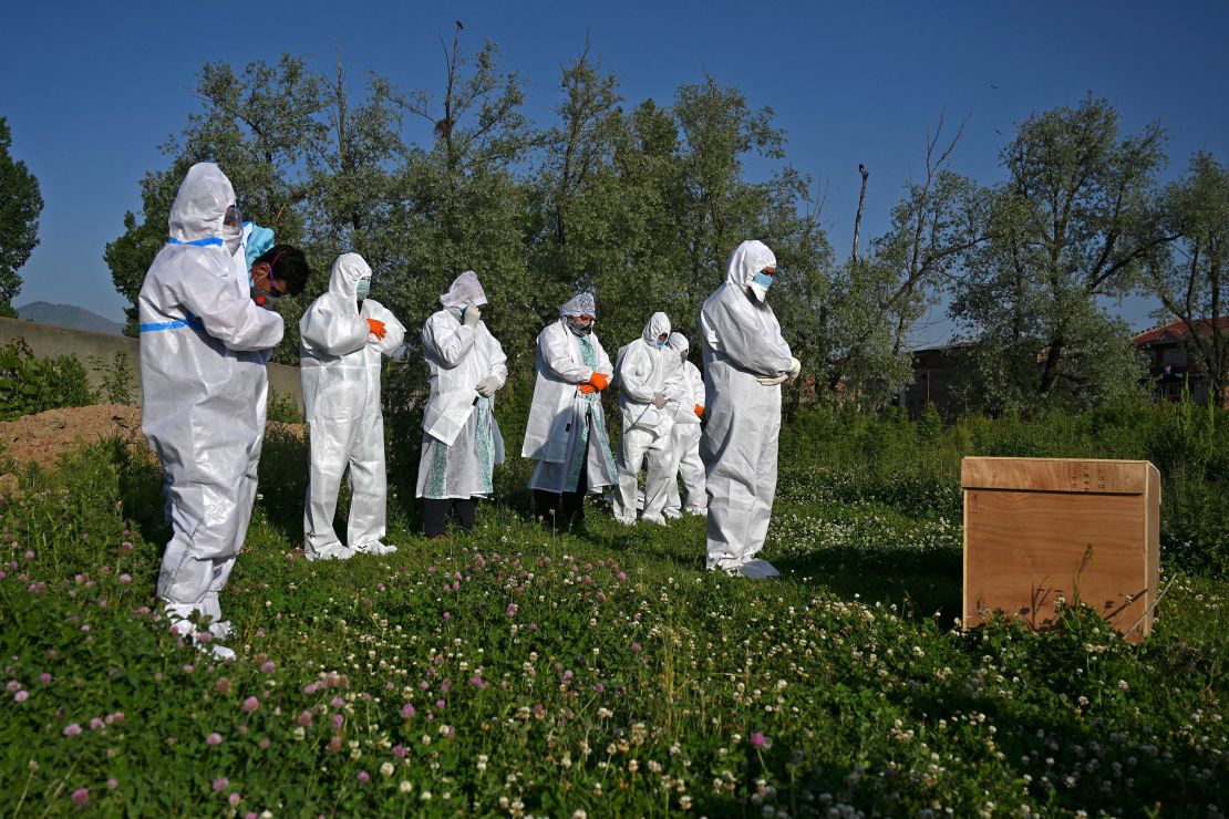 Relatives wearing personal protective equipment offer funeral prayers for a woman who died from the coronavirus, during her burial at a graveyard in Srinagar on May 21, 2020. 