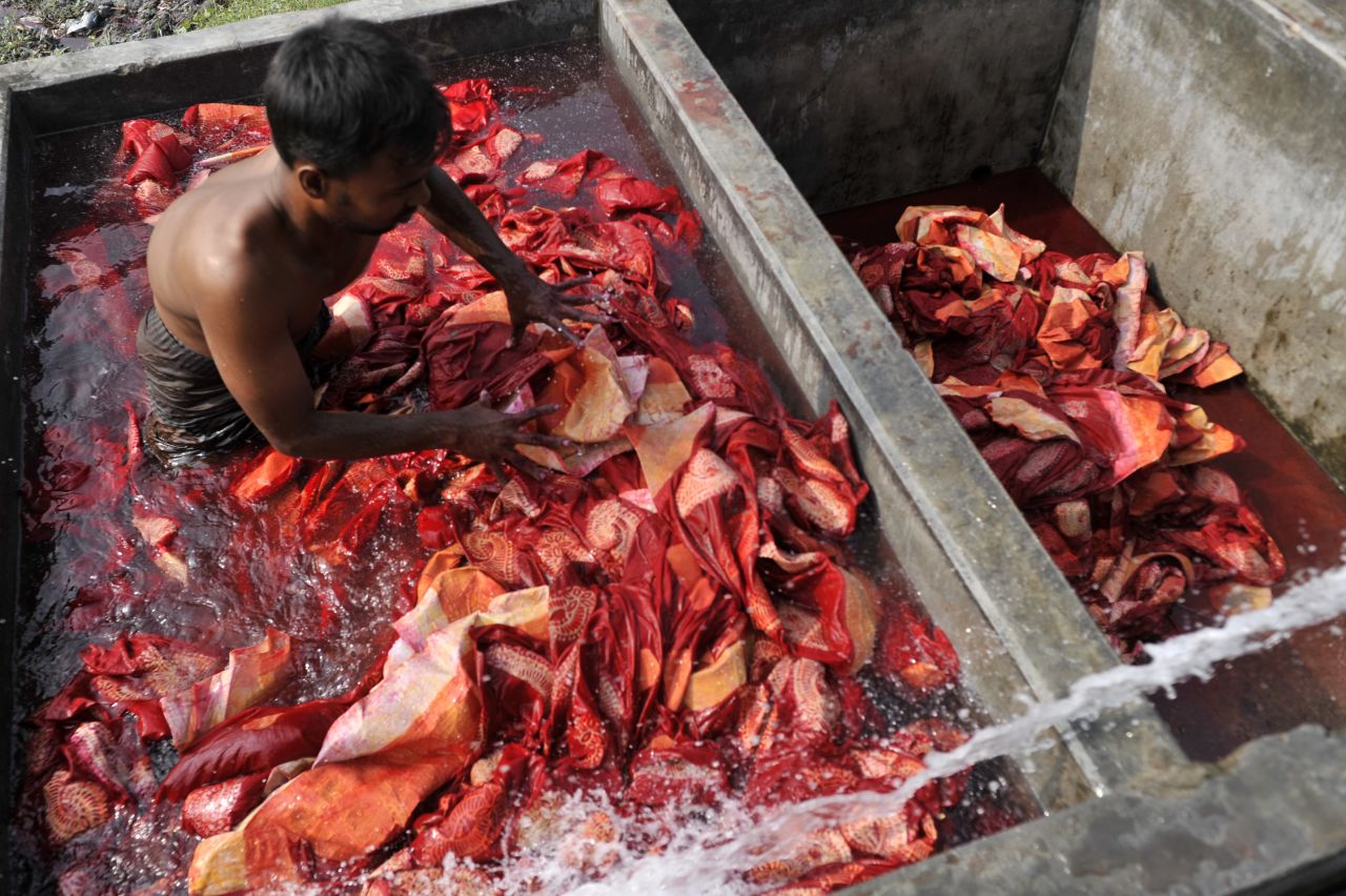 A boy mixes fabric in a pond of dye to ensure that the proper color will be achieved in a factory in Narayangonj, near Dhaka in November 2013.