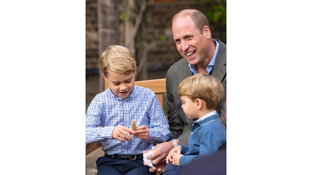 Prince William and Prince Louis examine the tooth of a giant shark given to them by Naturalist Sir David Attenborough in the gardens of Kensington Palace in London.