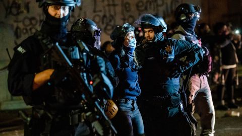 Police detain a protester outside the justice center building early Sunday in Portland.