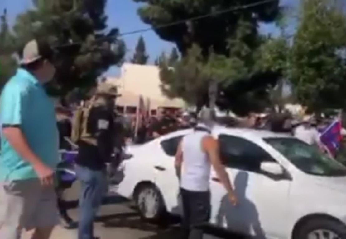 A car drives through a crowd of people at a protest in Yorba Linda, California.