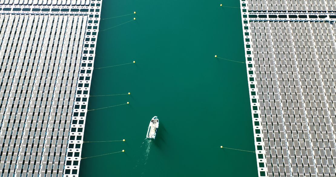 A boat navigates a channel between floating solar arrays at a facility built by Akuo Energy in the Rhone Valley, France. The Solar Impulse Foundation supports around 400 for-profit organizations offering green solutions.