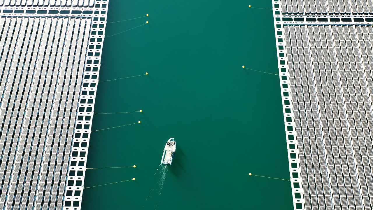 A boat navigates a channel between floating solar arrays at a facility built by Akuo Energy in the Rhone Valley, France. The Solar Impulse Foundation supports around 400 for-profit organizations offering green solutions.
