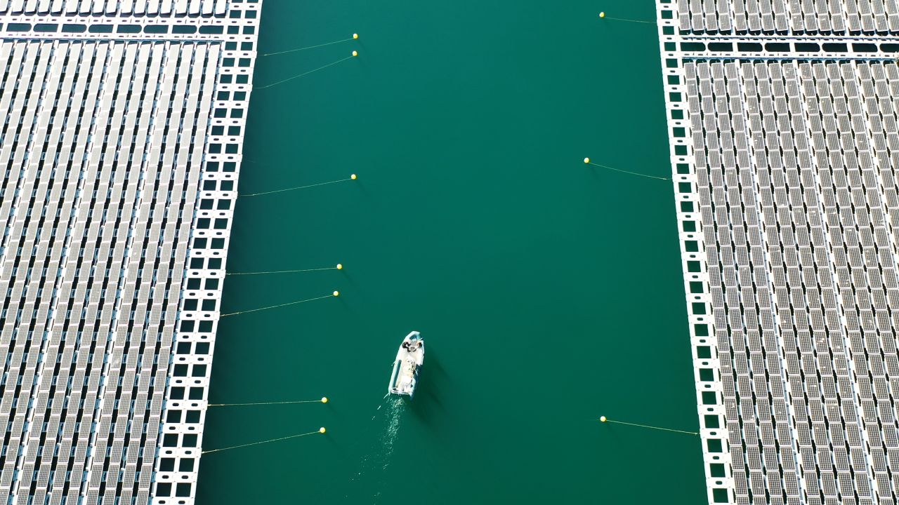 A boat navigates a channel between floating solar arrays at a facility built by Akuo Energy in the Rhone Valley, France. The Solar Impulse Foundation supports around 400 for-profit organizations offering green solutions.