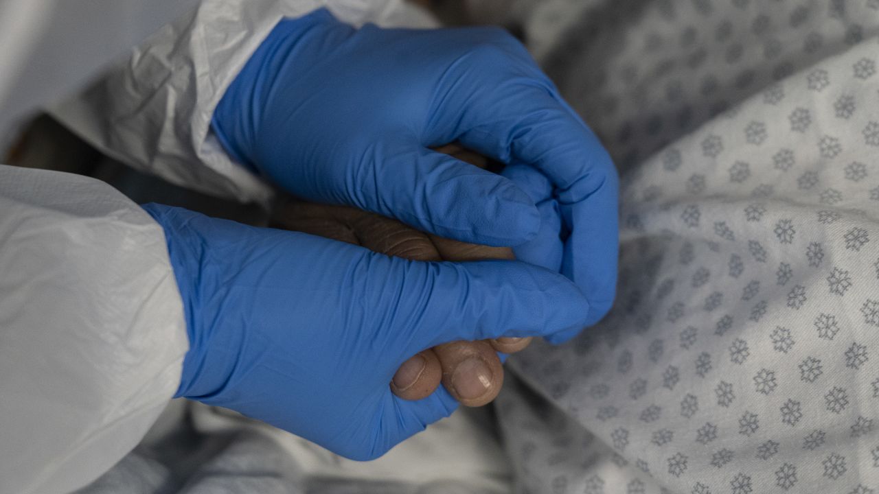 HOUSTON, TX - JULY 28: (EDITORIAL USE ONLY) A member of the medical staff holds a patient's hand in the COVID-19 intensive care unit at the United Memorial Medical Center on July 28, 2020 in Houston, Texas. COVID-19 cases and hospitalizations have spiked since Texas reopened, pushing intensive-care units to full capacity and sparking concerns about a surge in fatalities as the virus spreads. (Photo by Go Nakamura/Getty Images)