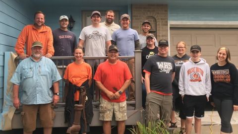Tim Gjoraas, wearing a black shirt in the front row, stands with the group of volunteers in front of his newly painted house.