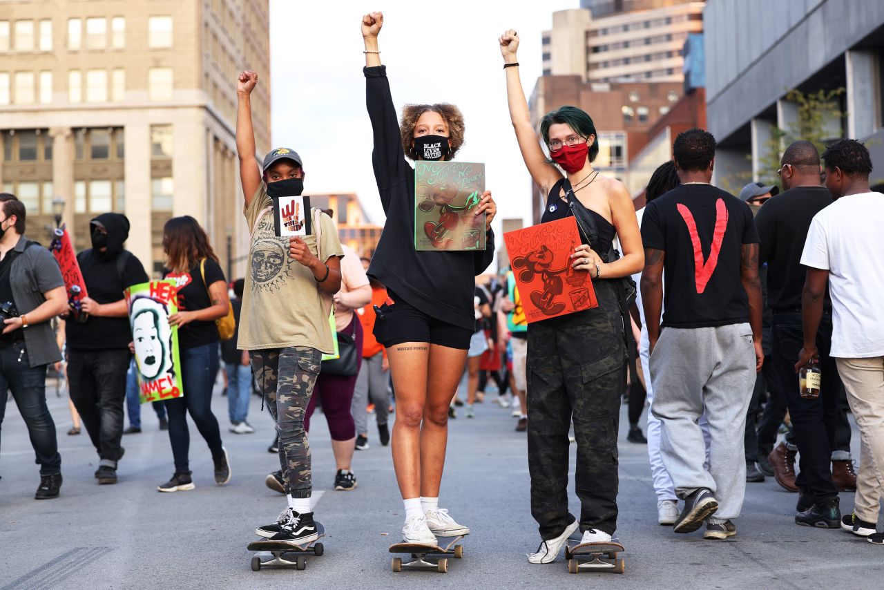 Courtney Anderson, Karr Young and Cailin Wilson hold up signs while skateboarding as they join a protest in Louisville, Kentucky, on September 26.