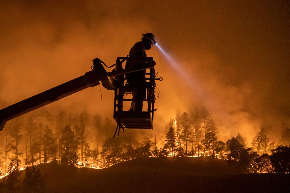 The Glass Fire burns in the background as Josh Asbury, an employee of CableCom, installs fiber-optic cable in Calistoga on September 28, 2020.