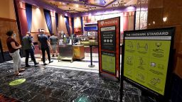 Customers line up near a sign displaying new safety and cleaning procedures at Cinemark's Century 16 at the South Point Hotel & Casino on August 14, 2020 in Las Vegas, Nevada. Cinemark reopened some of its movie theaters across the country today, with new safety precautions in place, for the first time since closing in March because of the coronavirus (COVID-19) pandemic. According to Cinemark, enhanced cleaning operations now include daily disinfection of auditoriums, sanitizing high-traffic spaces every 30 minutes, and cleaning all occupied seats in reduced-capacity theaters between every show. Showtimes are staggered to prevent crowding in hallways, lobbies and restrooms, and when tickets are purchased, adjacent seats are blocked off. The theater chain is encouraging purchasing tickets online or in the theater using contactless payment only since they no longer need to be handed to ushers. The theaters are currently screening "Comeback Classic" films with "Welcome Back" ticket prices of USD 5 for adults and USD 3 for children and seniors, the company said.  (Photo by Ethan Miller/Getty Images)