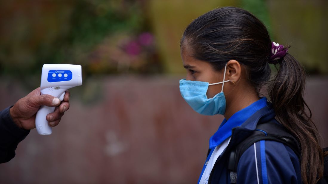 A student has her temperature checked before entering classes at a school in Thankot, Nepal, on September 30.