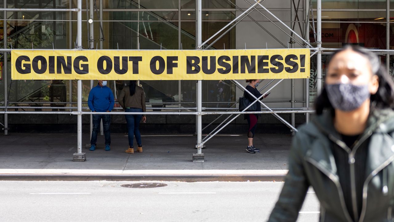 A woman wearing a mask walks by a "going out of business" sign as the city continues Phase 4 of re-opening following restrictions imposed to slow the spread of coronavirus on September 20, 2020 in New York City. The fourth phase allows outdoor arts and entertainment, sporting events without fans and media production. (Photo by Alexi Rosenfeld/Getty Images)