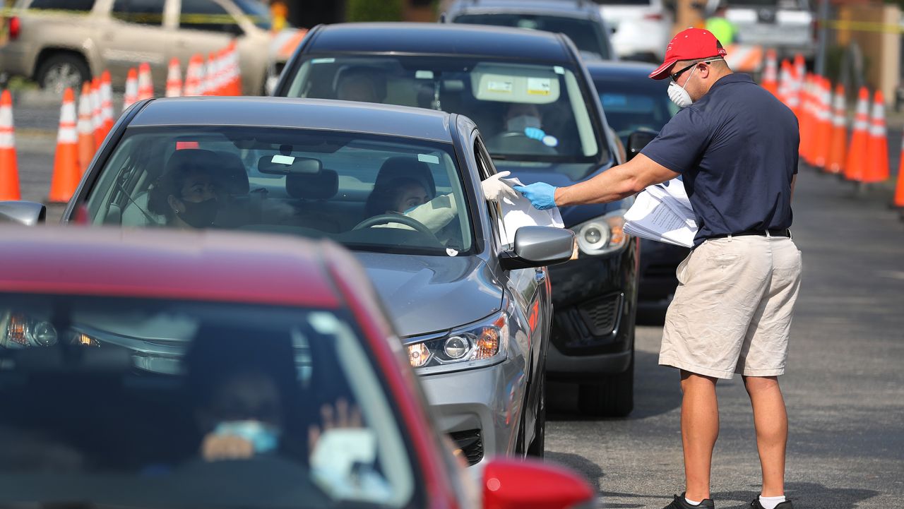 HIALEAH, FLORIDA - APRIL 08: Miguel Diaz, who works for the City of Hialeah, hands out unemployment applications to people in their vehicles in front of the John F. Kennedy Library on April 08, 2020 in Hialeah, Florida. The city is distributing the printed unemployment forms to residents as people continue to have issues with access to the state of Florida's unemployment website in the midst of widespread layoffs due to businesses closing during the coronavirus pandemic. (Photo by Joe Raedle/Getty Images)