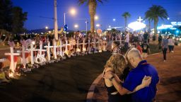 A small group prays at a makeshift memorial with 58 white crosses, one for each victim, on the south end of the Las Vegas Strip.
