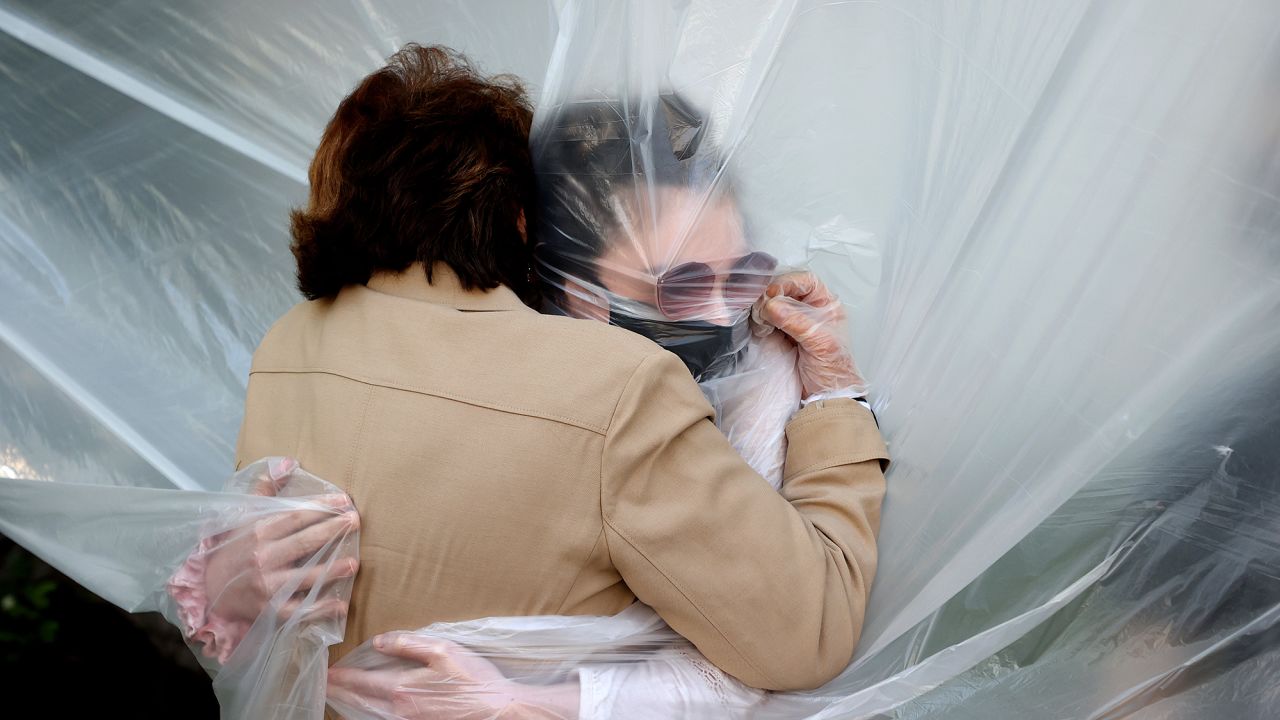 Olivia Grant hugs her grandmother Mary Grace Sileo through a plastic cloth in Wantagh, New York.