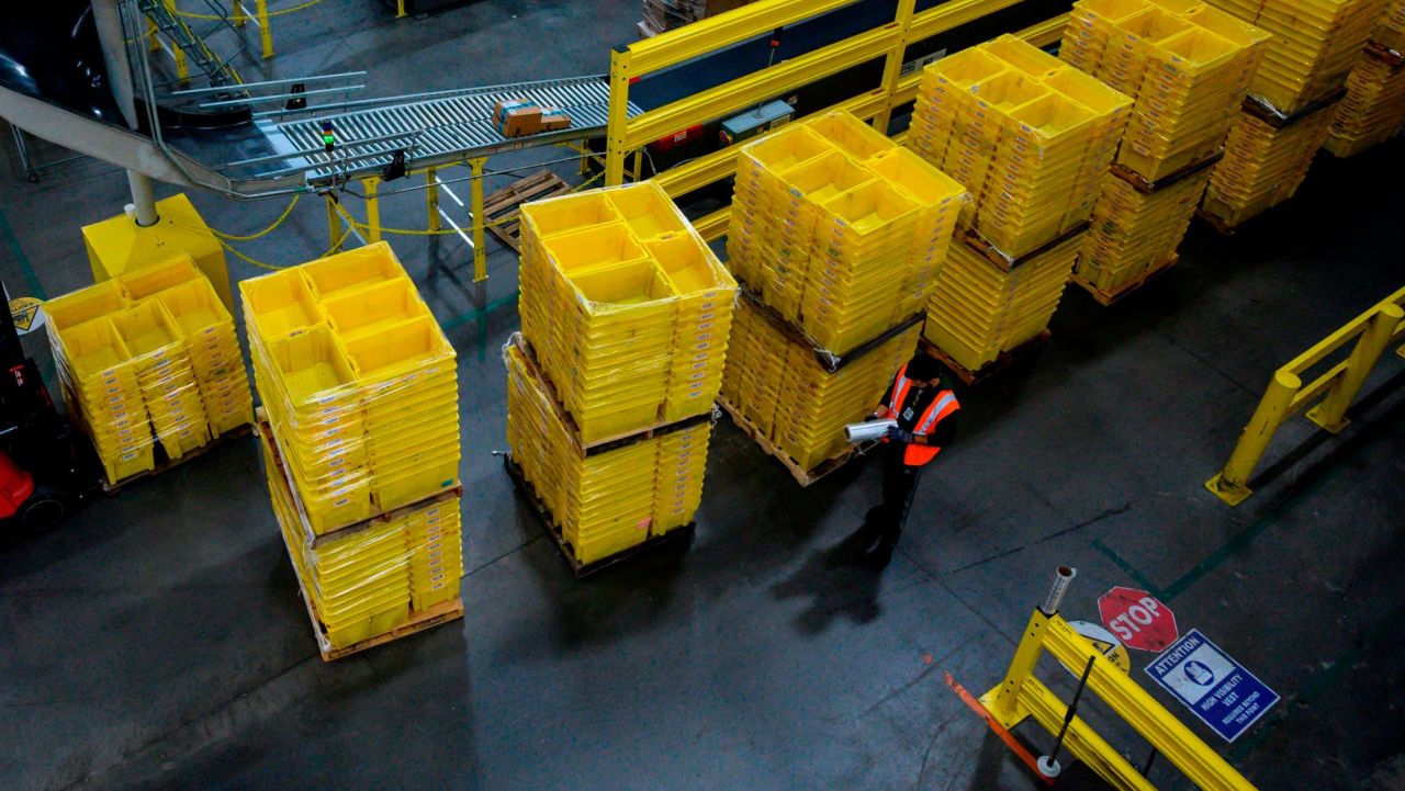 A man works at a distrubiton station at the 855,000-square-foot Amazon fulfillment center in Staten Island, one of the five boroughs of New York City, on February 5, 2019. - Inside a huge warehouse on Staten Island thousands of robots are busy distributing thousands of items sold by the giant of online sales, Amazon. (Photo by Johannes EISELE / AFP)        (Photo credit should read JOHANNES EISELE/AFP via Getty Images)