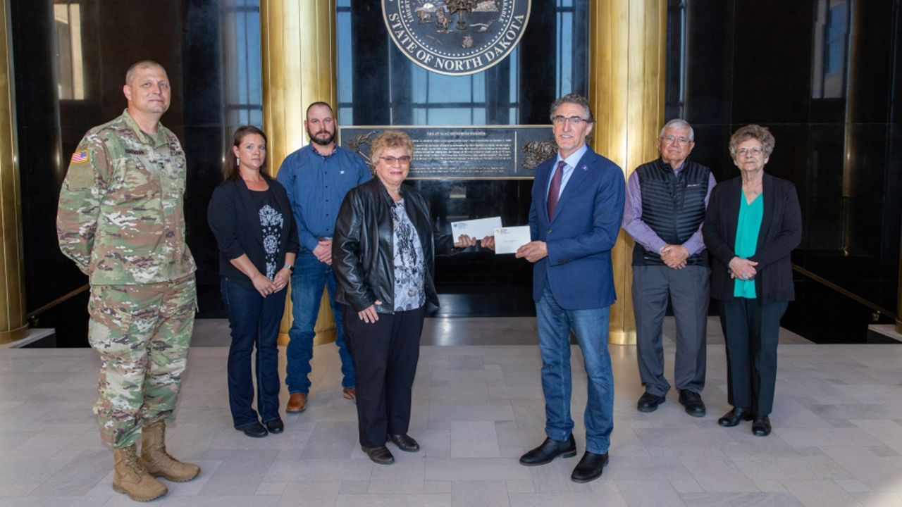 Gov. Doug Burgum presents Ronald Hepper's dog tag to his wife Ruth. They were joined by (from left) Maj. Gen. Al Dohrmann, Hepper's daughter Julie Hornbacher and her husband, Jim, and Ron Hepper's brother Stanley Hepper and his wife, Kathleen.