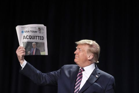 Trump holds up a newspaper at the National Prayer Breakfast in February 2020. It was a day after he was acquitted in his impeachment trial.