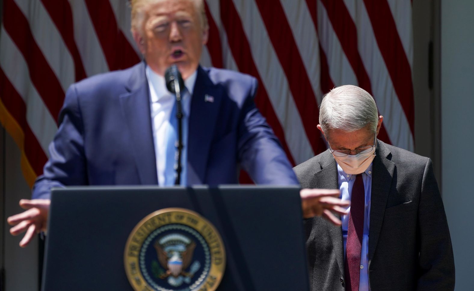 Dr. Anthony Fauci, director of the National Institute of Allergy and Infectious Diseases, looks down as Trump speaks in the White House Rose Garden in May 2020. Trump was unveiling <a href="index.php?page=&url=https%3A%2F%2Fwww.cnn.com%2F2020%2F05%2F15%2Fpolitics%2Ftrump-vaccine-effort-coronavirus%2Findex.html" target="_blank">Operation Warp Speed,</a> a program aimed at developing a coronavirus vaccine by the end of the year.
